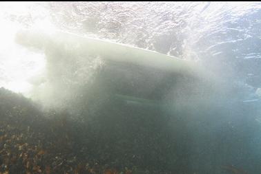 looking up at boat banging against rocks