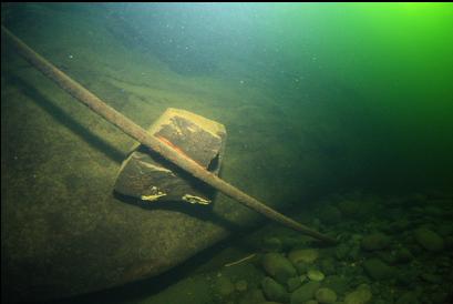 boulder leaning on metal rod